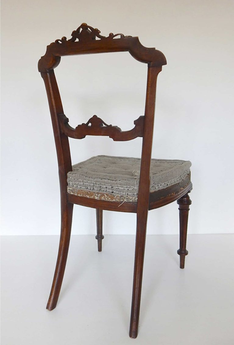 A traditionally upholstered walnut Victorian side chair. Back view.
