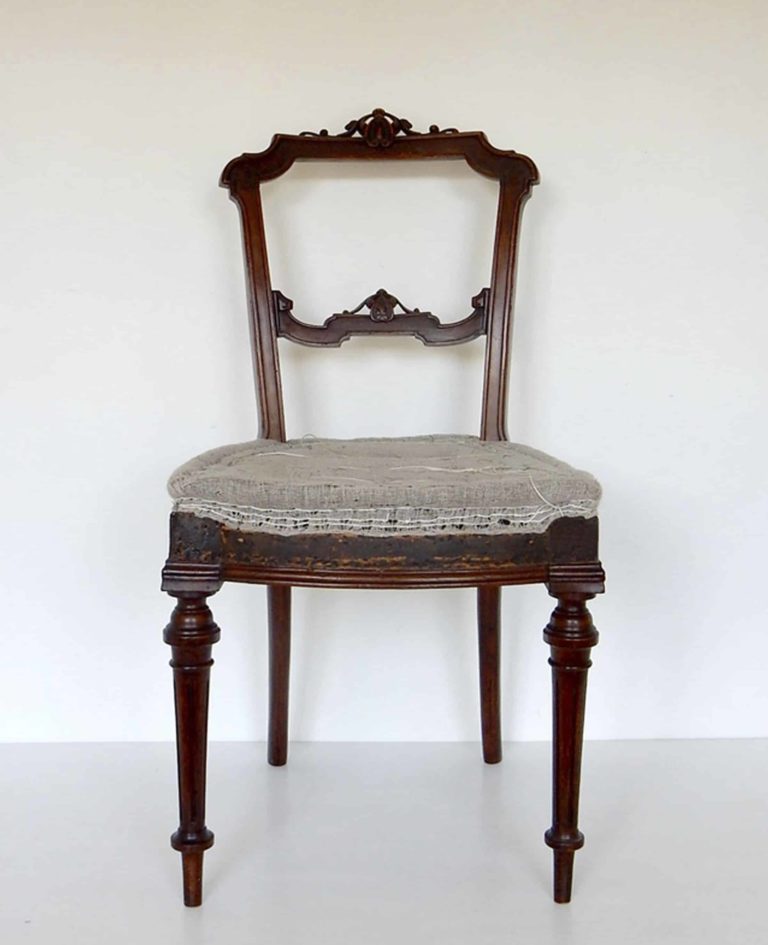A traditionally upholstered walnut Victorian side chair. Front view.