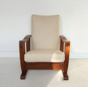 An Arts and Crafts oak reclining armchair upholstered in an oatmeal coloured basket weave fabric.