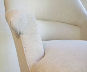Close-up of French fauteuil crapaud armchair scroll arm fabric pleats.
