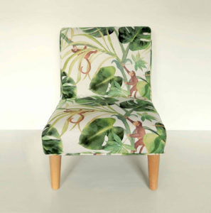Modern child’s chair; fabric decorated with little monkeys climbing through big green leaves.