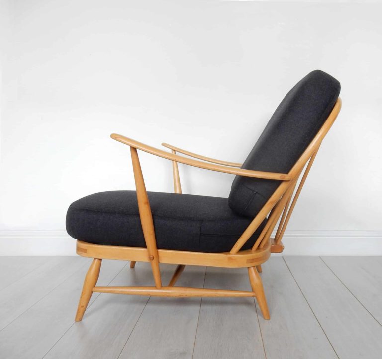 A classic, blonde wood Ercol 203 armchair: charcoal black wool cushions and sheepskin.