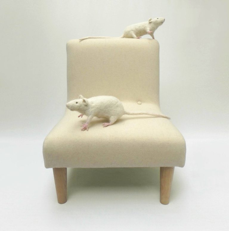 Two cute needle felted white rats sitting on a little chair, upholstered in pale cream wool fabric.