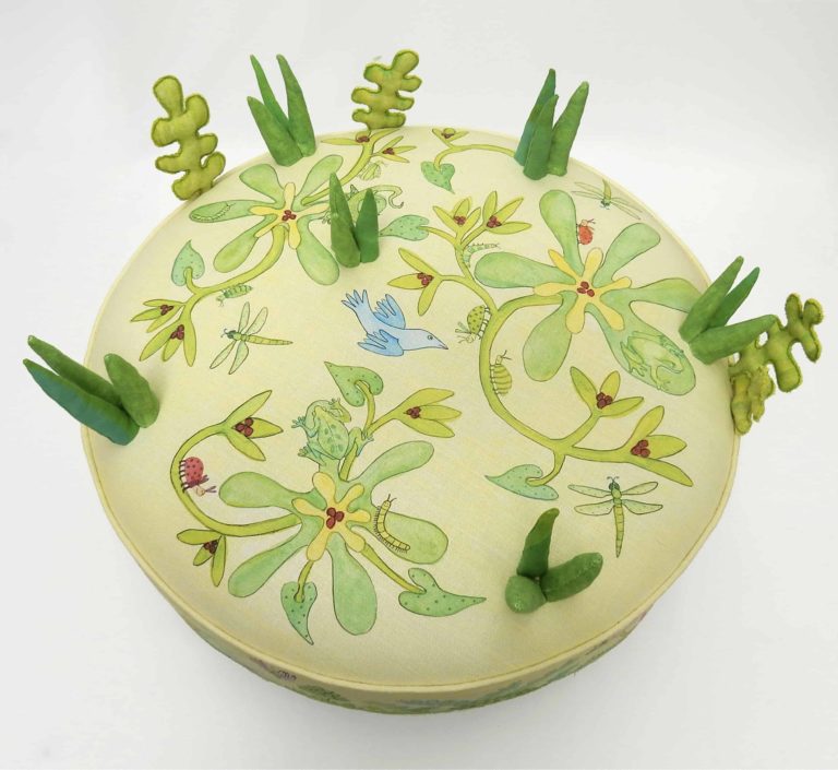 Child's large round play stool; printed with cute animals, bugs, birds, foliage, flowers; top view.
