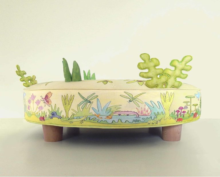 Child's round play stool; fabric printed with cute animals, bugs, birds, foliage, flowers. 3d grass and leaves stitched on top.