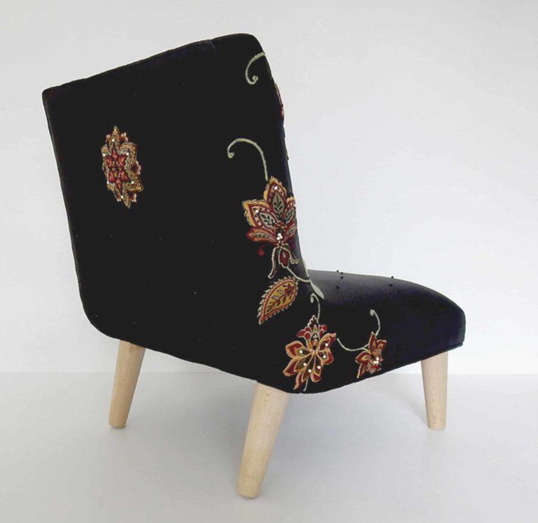 Child’s chair, appliqué fabric - white cat lying under red and gold embroidered flowers on black linen, back view.