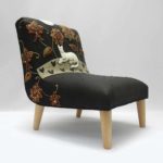 Child’s chair, appliqué fabric - white cat lying under red and gold embroidered flowers on black linen.