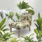 Cute, green fabric lizard sitting on a little chair, upholstered in floral botanical linen fabric, surrounded by real plants.