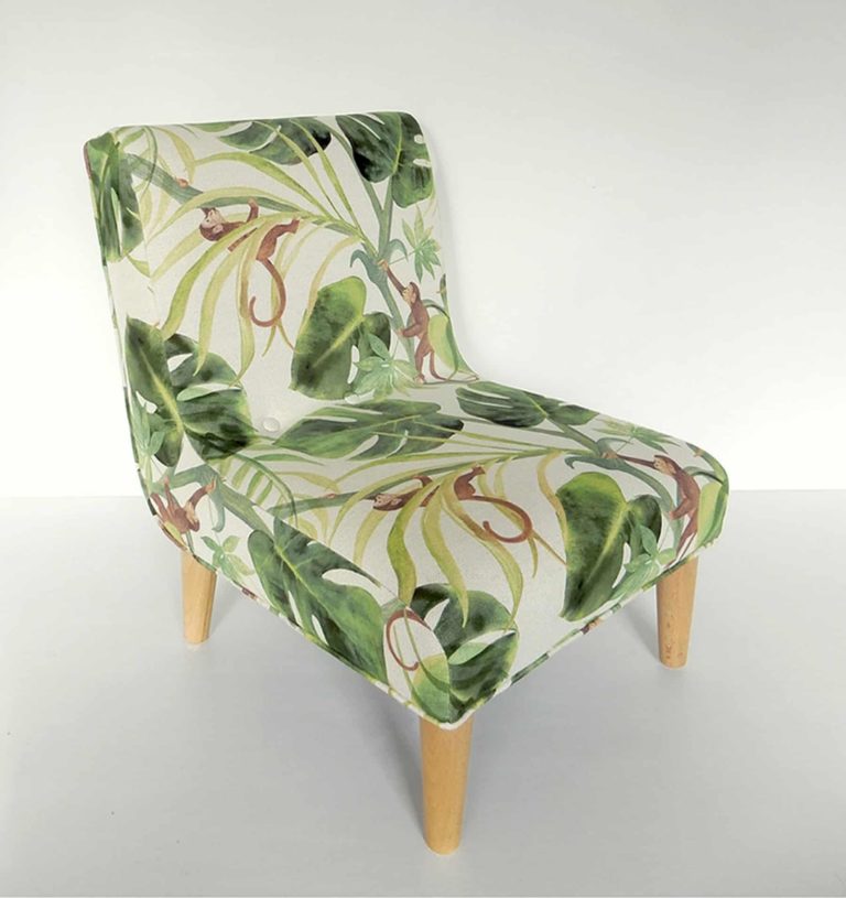Modern child’s chair; fabric decorated with little monkeys climbing through big green leaves. Right side view.de