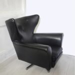 A vintage 1960s-70 swivel armchair in black vinyl fabric.; side view.