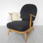 A classic Ercol 203 armchair: charcoal black wool cushions and sheepskin. Front view