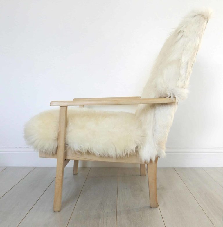 A vintage Parker Knoll armchair; sheepskin seat and goat hair on hide to back. Side view.