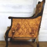 Old Edwardian library armchair with faded, worn upholstery: side view,