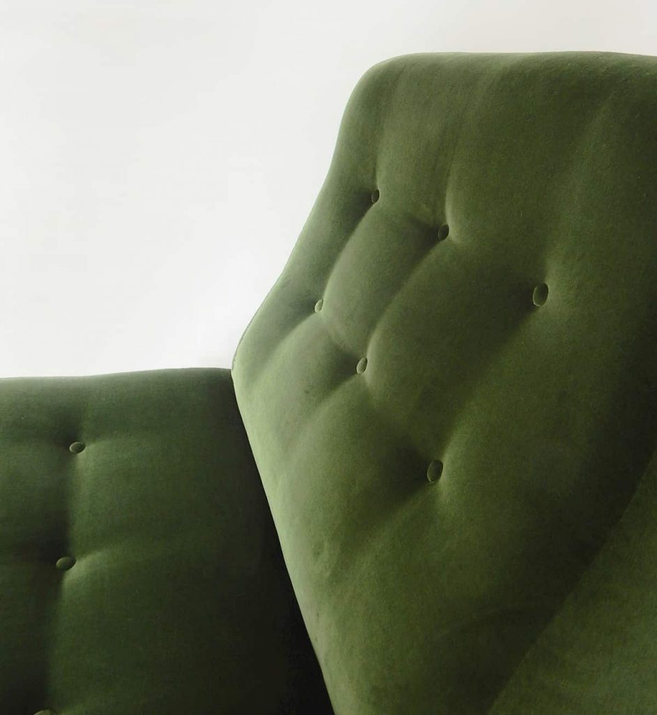 Newly upholstered retro swivel chair in forest green velvet by Designer’s Guild, close-up shallow buttoning.